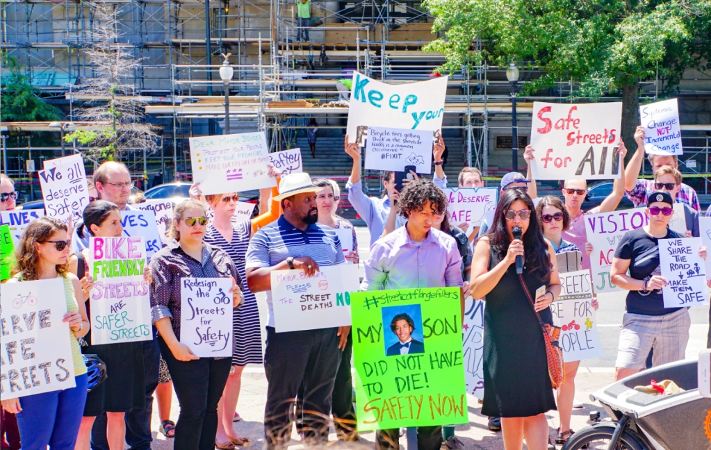 A protest in favor of Vision Zero in Washington D.C. A large group of people stand with protest signs expressing their support for life-saving strategies like road diets.